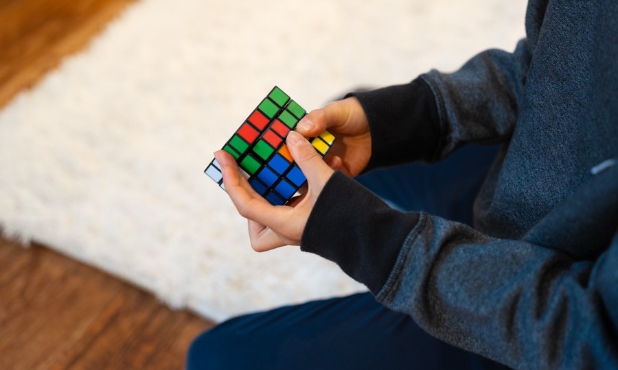 A child turning a Rubik's cube over in their hands, working a problem through step by step