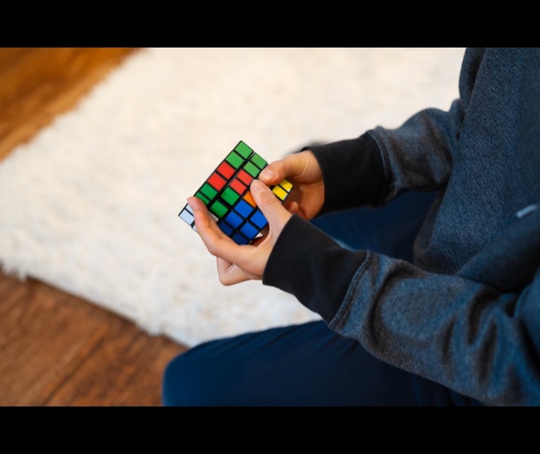 A child turning a Rubik's cube over in their hands, working a problem through step by step
