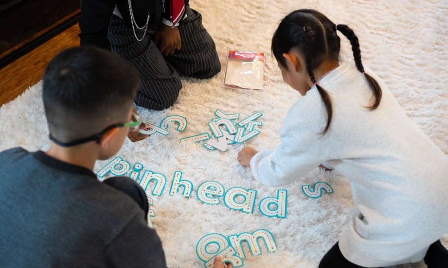 Two children forming letter shapes together on the floor